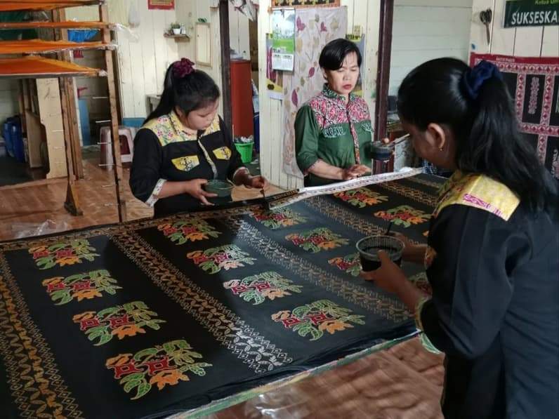 Tiga pengrajin batik sedang fokus menyelesaikan proses pewarnaan kain batik khas Paser. (Foto: Nuhraini Palipung)