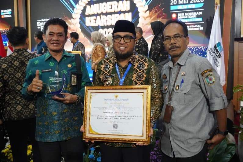 Wabup Paser Ikhwan Antasari (tengah) bersama Kepala Diskarpus Paser Yusuf Sumako (kiri) sembari memegang penghargaan Nominator Simpul Jaringan Terbaik Nasional. (Foto : Dok Prokopim Paser)
