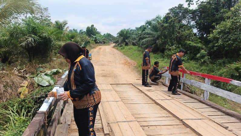 Proses pengecatan jembatan penghubung antara Desa Biu dan Desa Samurangau yang dilakukan personel Polsek Muara Samu. (Foto: Dok Humas Polres Paser)