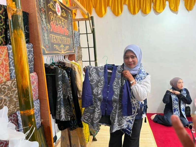 Sekretaris Diskoperindag Berau, Syamsiah Nawir, menunjukkan salah satu produk busana berbahan tenun khas Berau. (Foto: Nur Hidayah/ pusaranmedia.com)