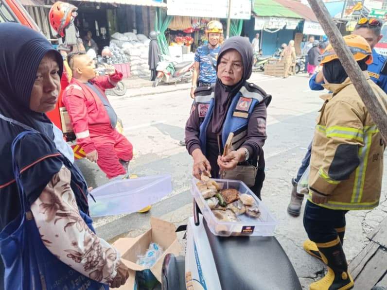 Mama Ica membagikan wadai dagangannya ke petugas pemadam kebakaran, Jumat (31/7/2026). (Foto:Achmad Fadillah/Pusaranmedia.com)